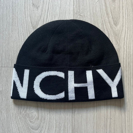 Black Givenchy Jacquard beanie made from 100% wool and crafted in Italy. Features the white contrasting logo around the rolled brim, splitting “GIVE” and “NCHY” across the hem. Premium construction with a soft, comfortable fit.