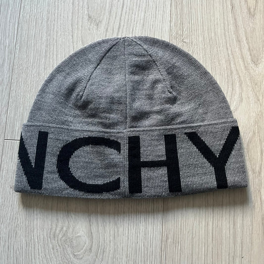 Gray Givenchy Jacquard beanie made from 100% wool and crafted in Italy. Features the black contrasting logo around the rolled brim, splitting “GIVE” and “NCHY” across the hem. Premium construction with a soft, comfortable fit.
