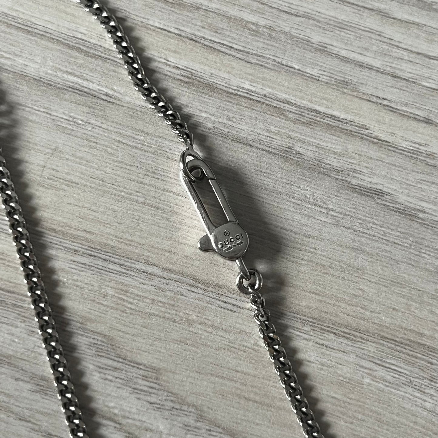 Close-up of a silver chain with clasp on a textured gray surface
