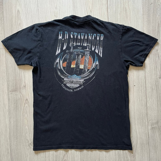 Black Harley Davidson t-shirt from 2011 with striking skull and Harley branding on the chest. Back print features the Stavenger Norway logo and date for an authentic rally vibe. Perfect for fans of vintage motorcycle style.