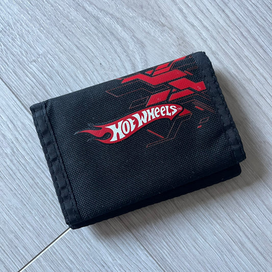 2008 Hot Wheels 24/Seven wallet in black with a detailed blue 24/Seven Car graphic under a protective plastic laminate. Includes Hot Wheels logo detailing, Mattel tags, and plenty of compartments for storage. A functional piece with nostalgic collector appeal.