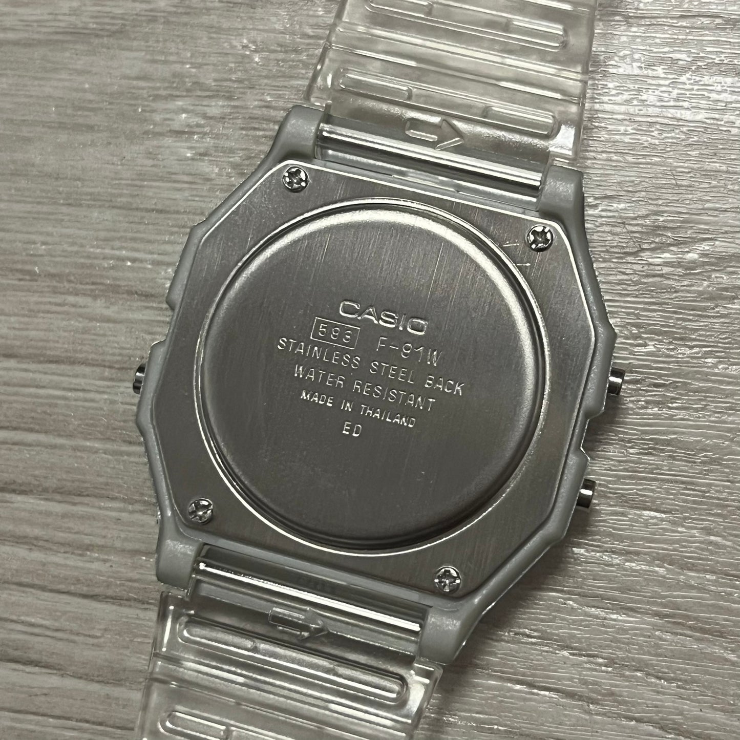 Back of a Casio watch with text on a wooden surface