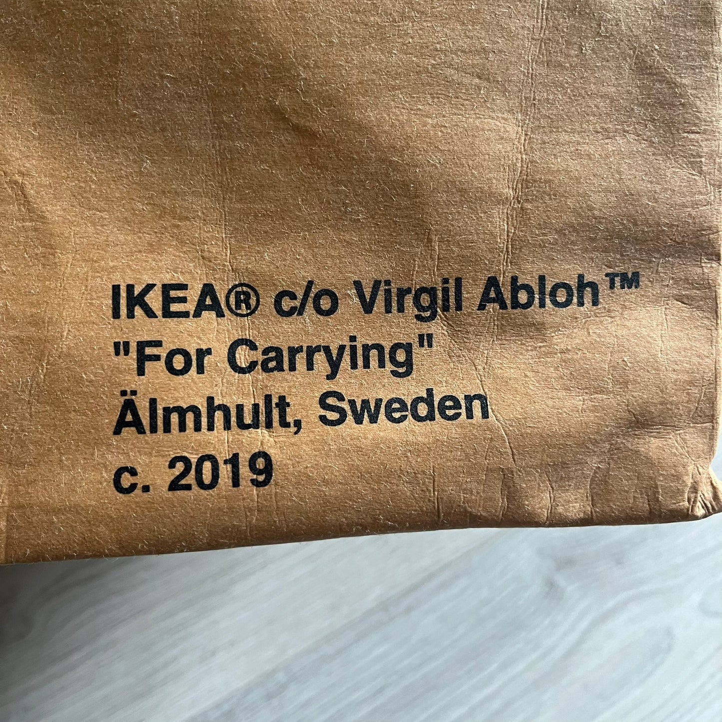 Ikea x Virgil Abloh Markerad "Sculpture" Carrier Bag from FW19 reimagines the iconic blue Frakta tote in reinforced brown paper. Embellished with Abloh’s signature quotation marks, the “SCULPTURE” print transforms a utilitarian object into conceptual design. A collectible symbol of functional art and everyday irony.
