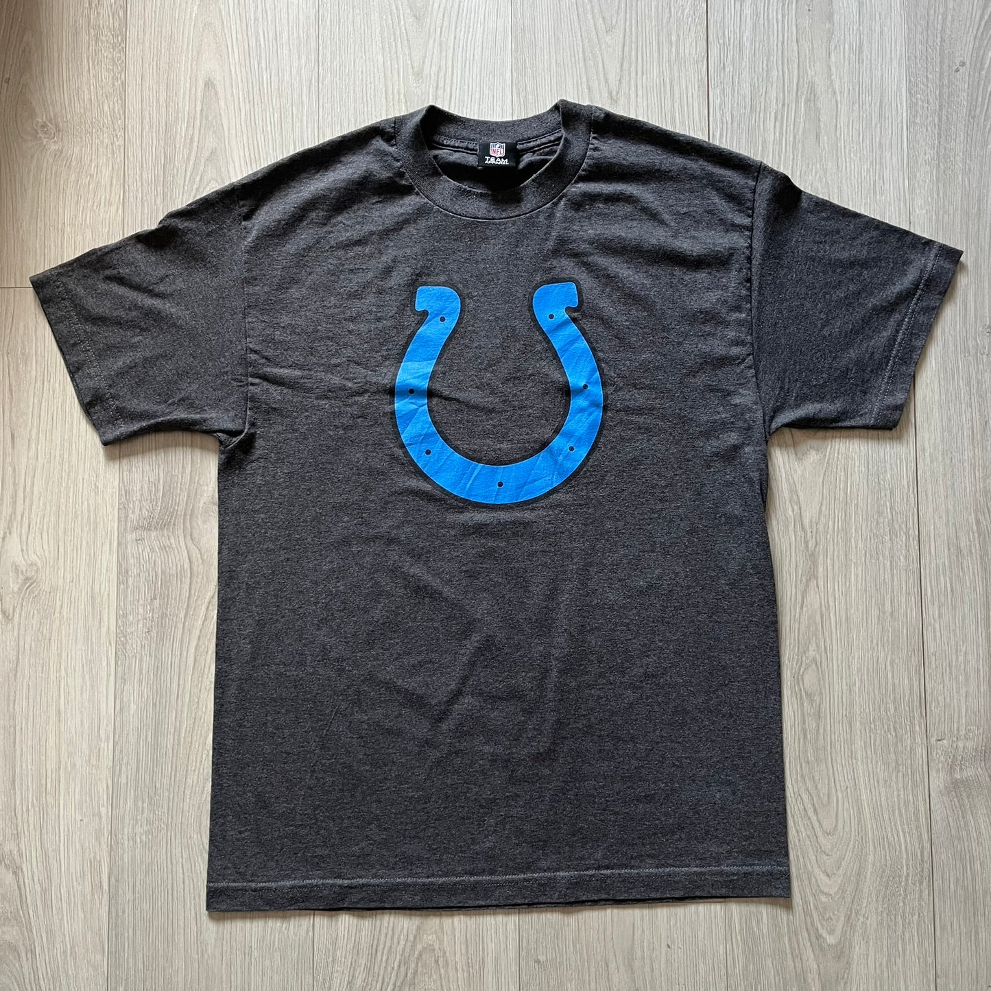 Gray t-shirt with blue logo on a wooden surface