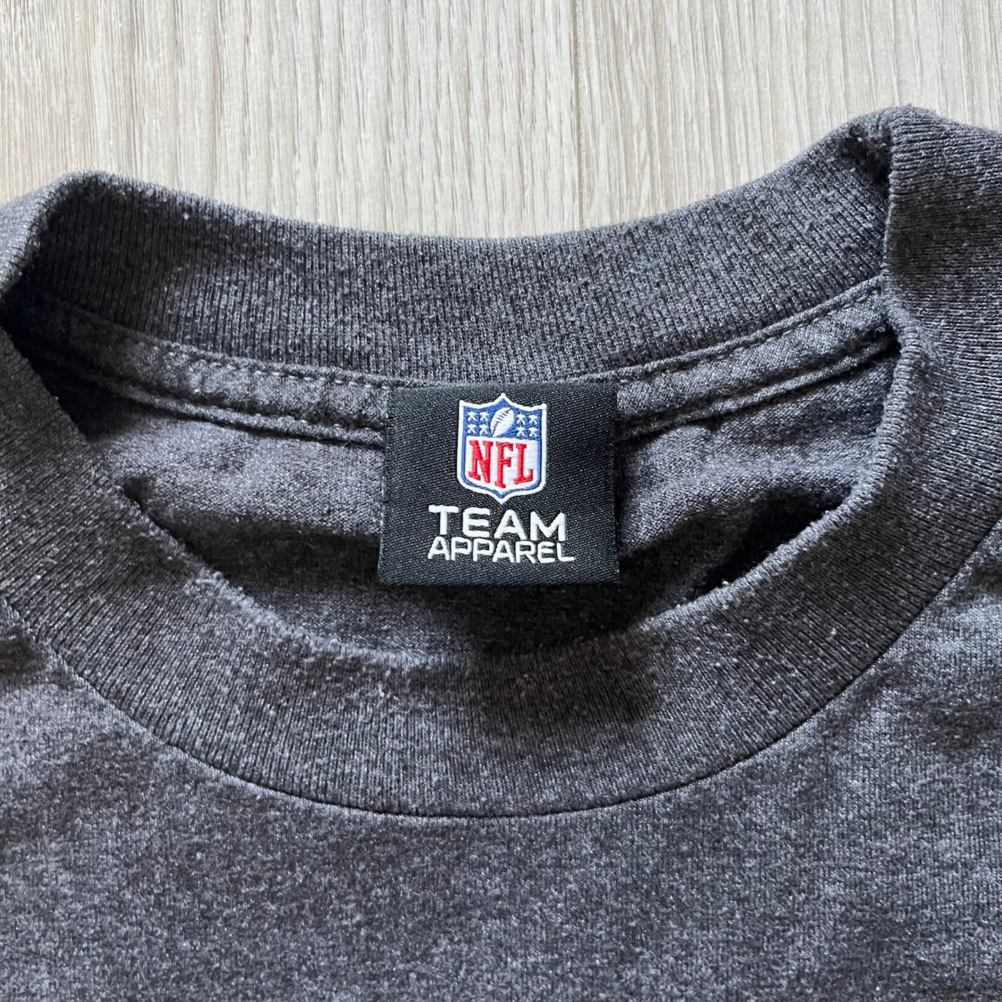 Gray shirt with NFL Team Apparel label on a wooden surface