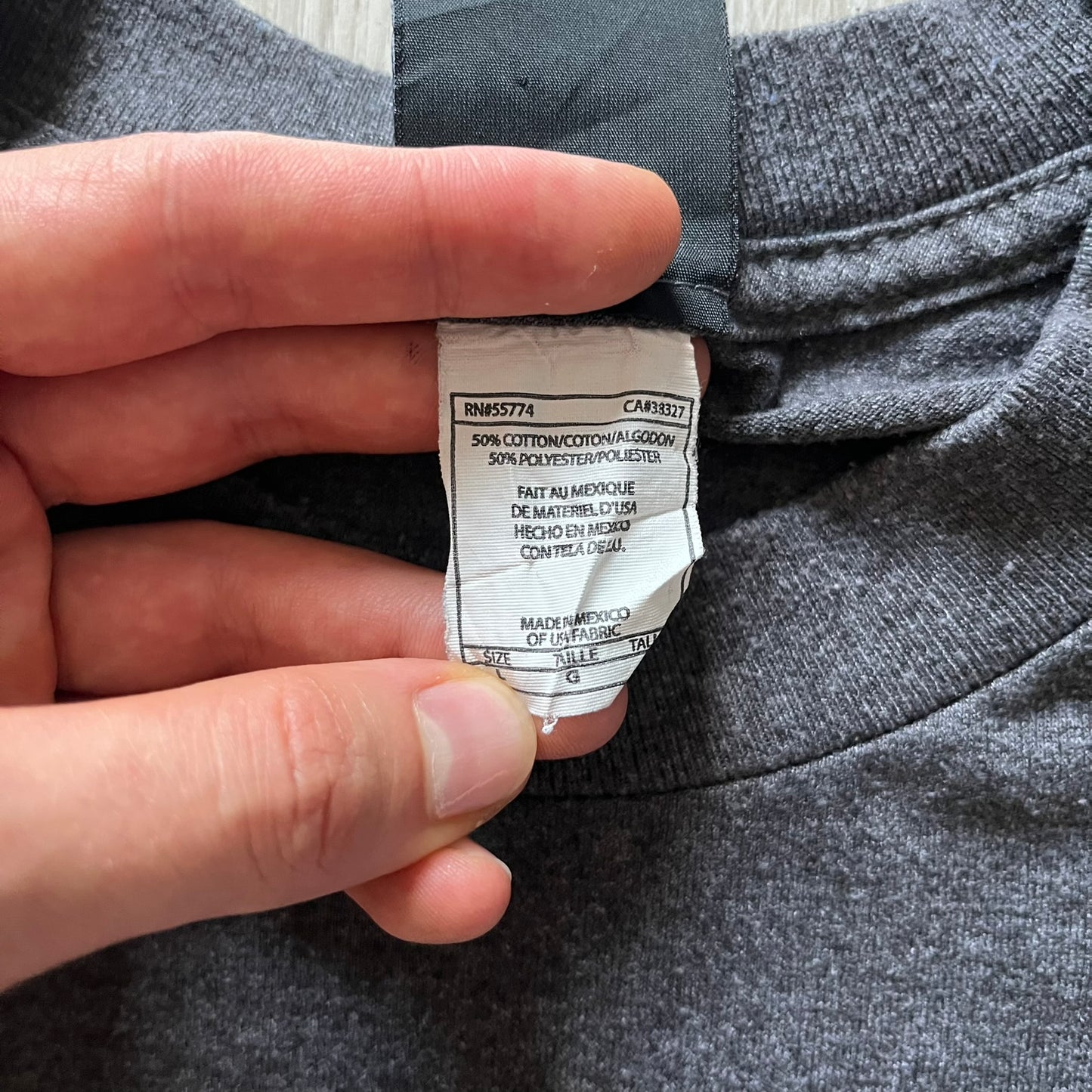 Hand holding a clothing label on gray fabric