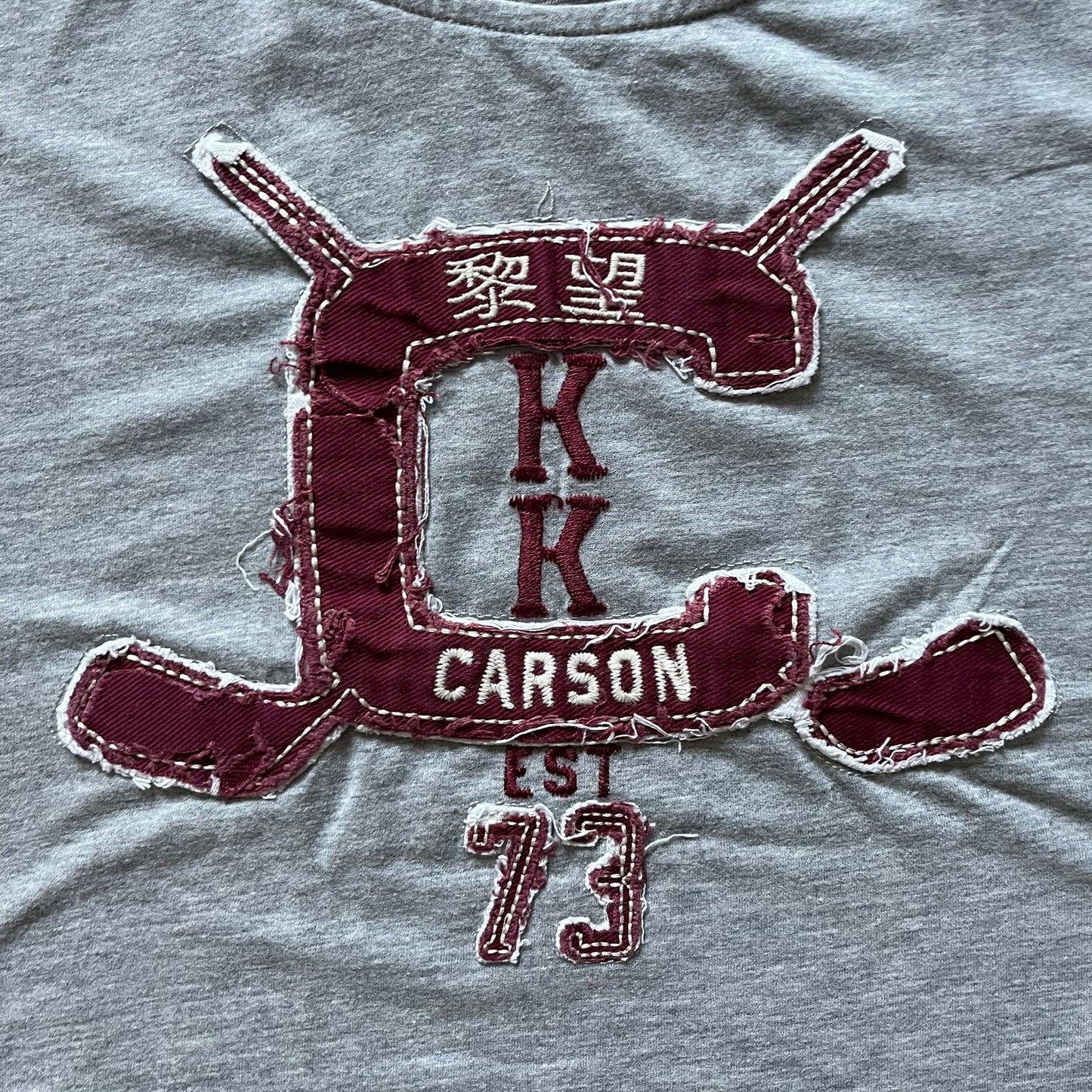 Maroon patch with 'Carrson' text on a gray fabric background