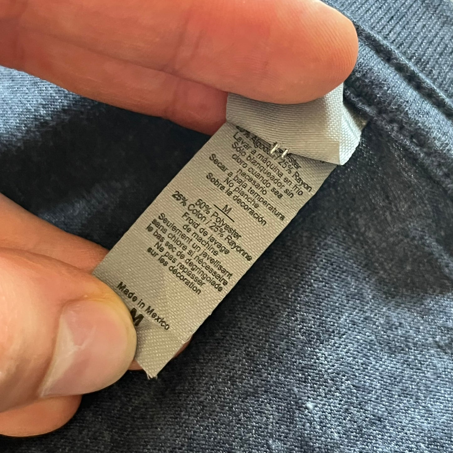 Close-up of a clothing label on a garment with a hand holding it.