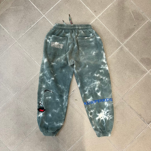 KidSuper Studios FW21 Tie-Dye Sweatpants feature a white and grey tie-dye colorway with multiple embroidered details throughout. The sweatpants include a blue KidSuper logo, eye graphics, “Resenha” text, text on the drawstrings, and additional embroidery on the back pockets. Finished with a pink size tag.