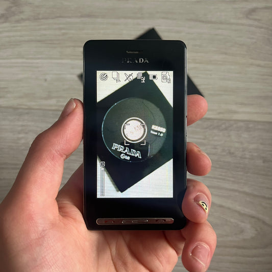 The LG Prada KE850, a groundbreaking collaboration between LG and Prada marked the world’s first capacitive touchscreen phone. Finished in sleek black with minimalist Prada aesthetics, it features media playback, Bluetooth, and expandable memory. Includes the full original Prada set: box, charger, cable, music device, manuals, and CD. Unlocked and functional for basic functions; for calling and texting you need your own SIM card.