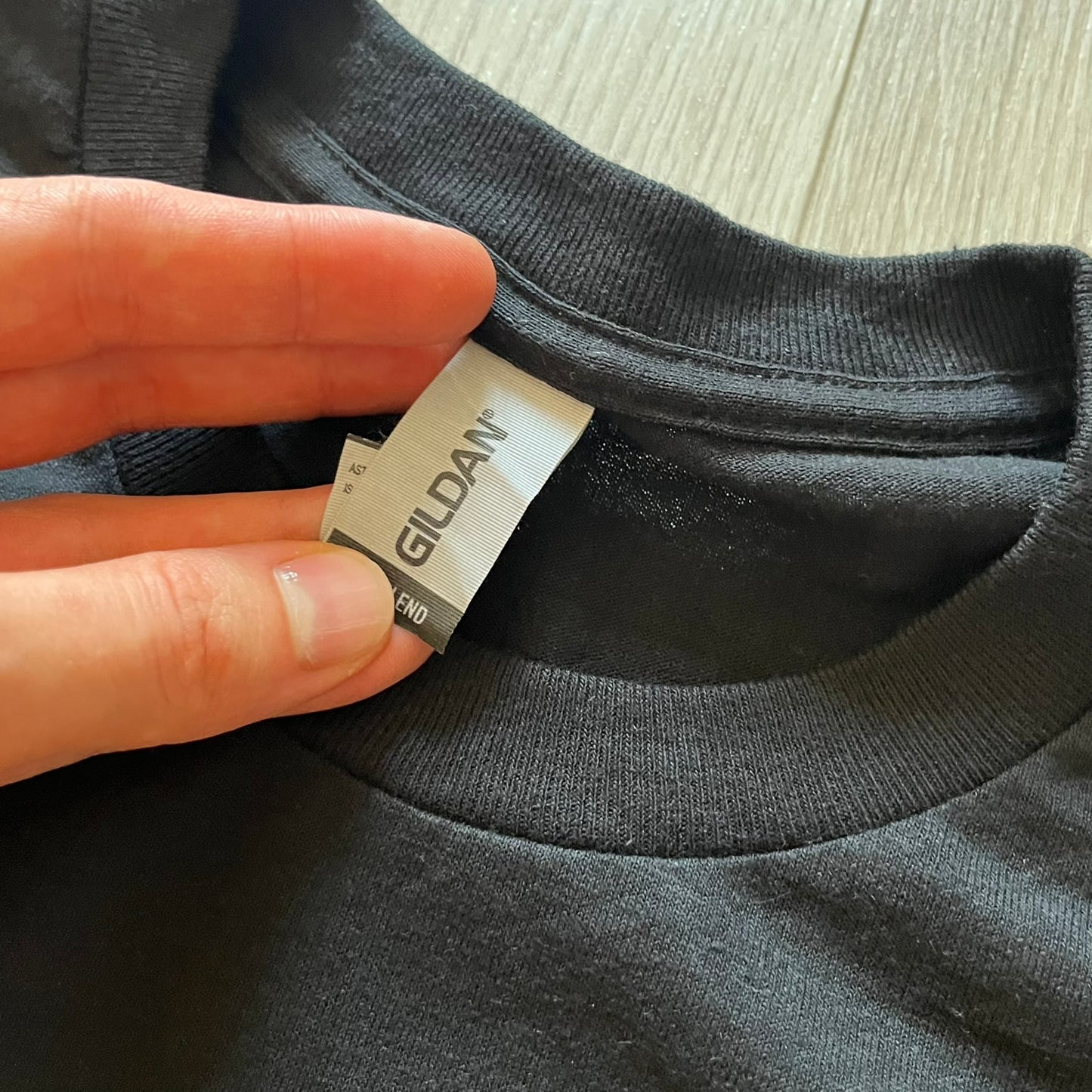 Hand holding a Gildan label on a black shirt