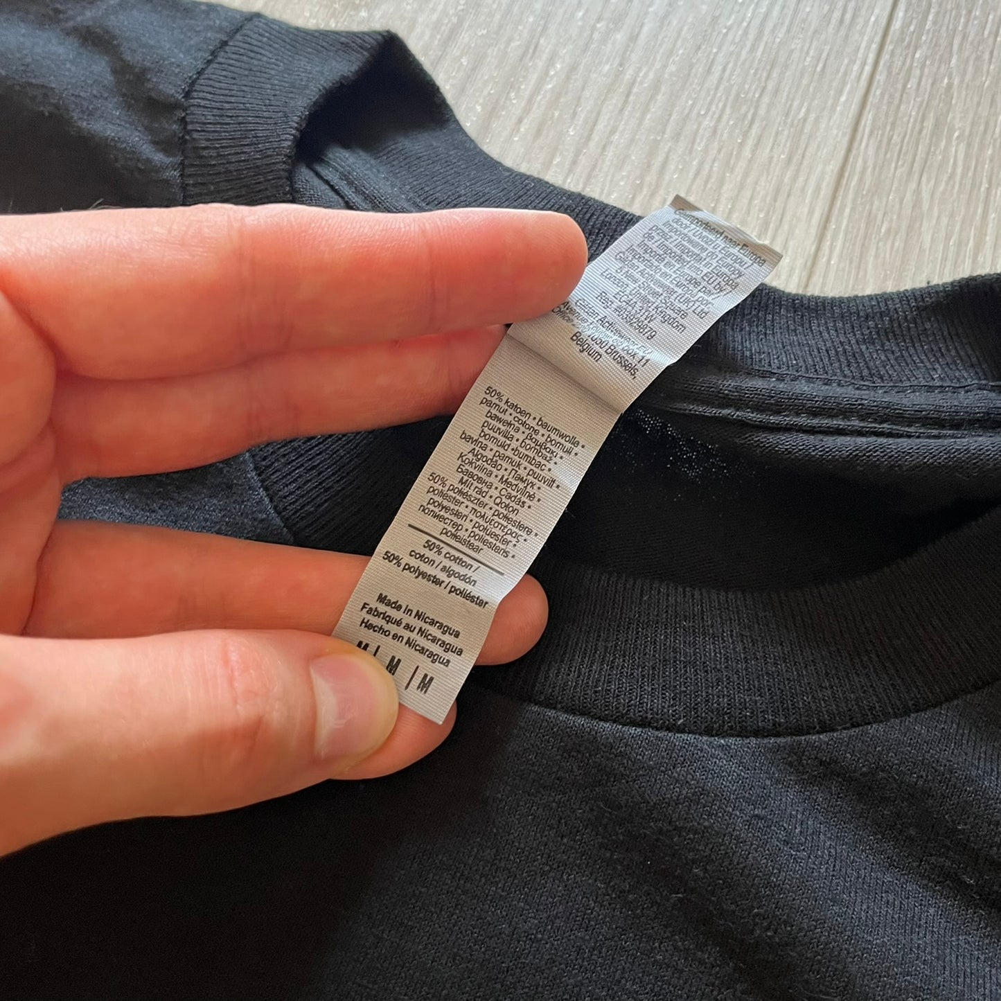 Hand holding a clothing label on a dark fabric background