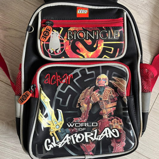 Lego Bionicle 2010 Glatorian Gresh Backpack made by Class Investment in 2010, featuring a front pocket with an embroidered Glatorian Ackar figure and text. The top pocket includes both Bionicle and LEGO logos, along with custom rubber zipper pulls. Finished with two side bottle pockets and additional Bionicle logo details, making it a great rare collectible for fans of the series.