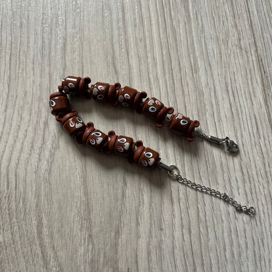 Lego Graduation Brick Bracelet featuring ten brown Lego bear heads from Kanye West’s Graduation era, set on a thin silver bracelet. The heads are standard Lego size and the piece comes in a custom-designed display box. Made by TheCanvasDon.