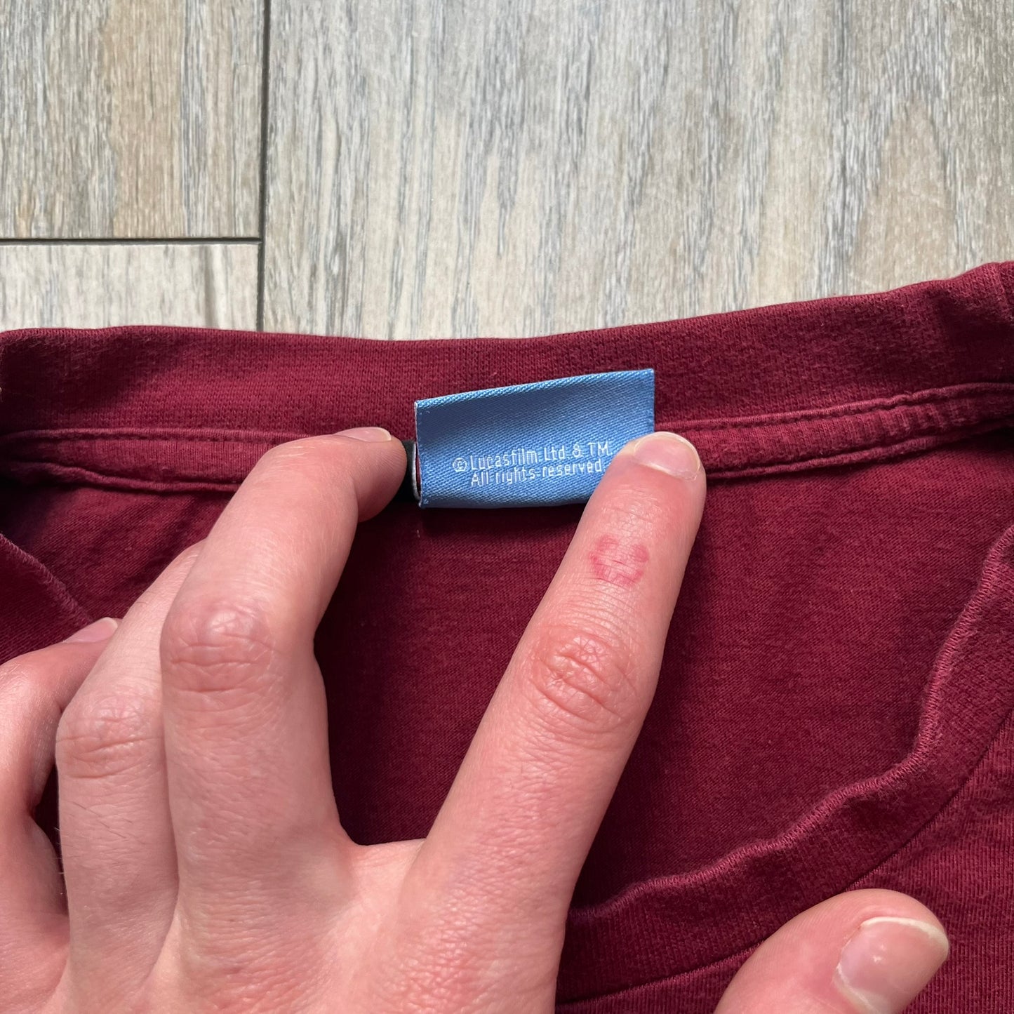 This Lego Star Wars 2008 Jedi Tee (Medium) in burgundy showcases Luke Skywalker wielding a blue lightsaber with a 'cracked' “I Am a Jedi” text. Officially licensed by Lego Star Wars, the tee includes authentic 2008 branding under the Luke minifigure graphic.
