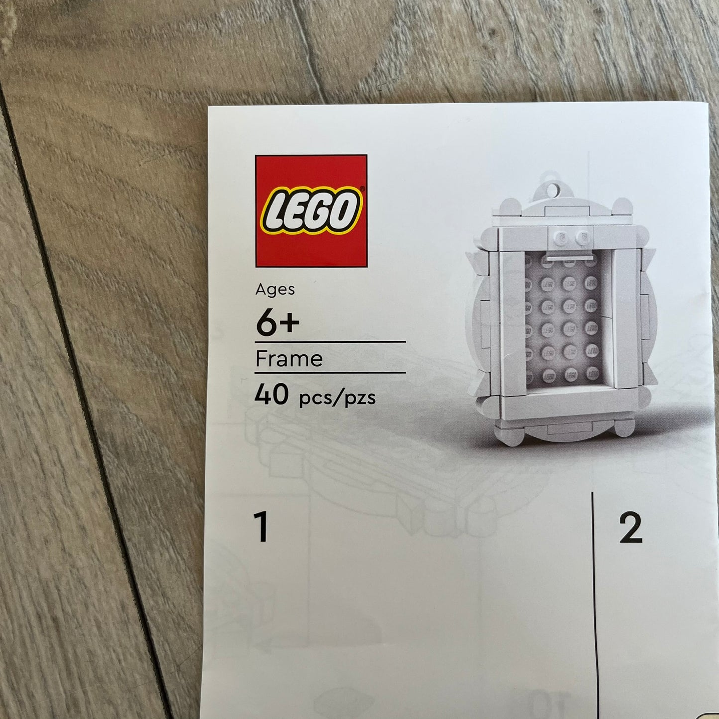 LEGO White Frame Make and Take Build is a limited promotional LEGO set distributed as an exclusive “make & take” event and not available for retail purchase. The model features a fully white 3D frame styled like a picture frame, designed for use as a photo holder. The back includes a hole for hanging or display.