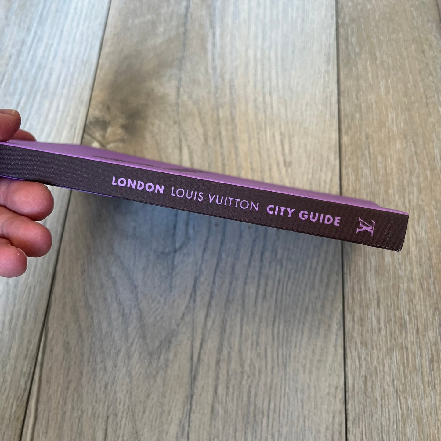 Louis Vuitton London City Guide is an English-language travel guide with a cloth-bound hardcover. It includes recommendations for hotels, restaurants, museums, shopping, and cultural locations across London. The edition features guest contributions by Richard Deverell, writing by Richard Cook, and exclusive photography by Grégoire Eloy.