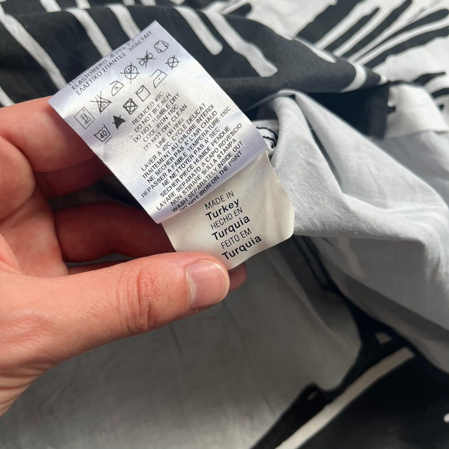 Love Moschino SS19 Dripping Paint Print Button-Up Shirt is a black and white shirt from the Spring/Summer 2019 collection. The upper portion is white, while the lower portion is black. The transition between the two sections features a dripping paint graphic extending downward from both sides into the black area. The button closure uses matching buttons, with white buttons on the white section and black buttons on the black section.