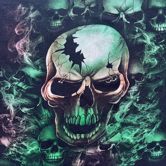 MC5 Boyc Skulls Tee in a wide, boxy-ish fit, crafted from high-quality cotton. The black tee features a large cracked skull with piercings on the front, surrounded by smaller skulls in white and green tones. A bold vintage-inspired graphic piece with strong visual impact.