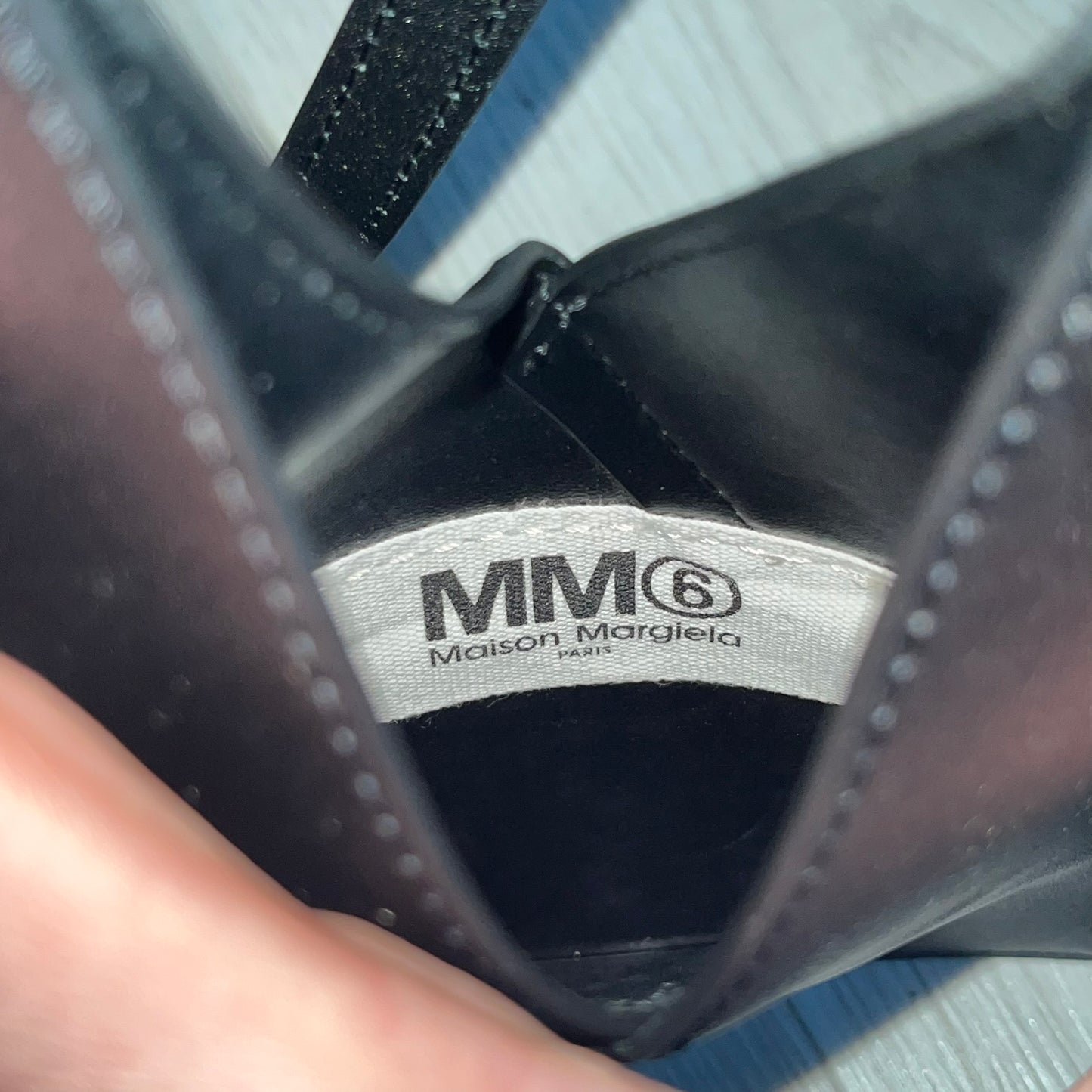 MM6 Maison Margiela Japanese 6 Accordion Phone Bag in black calf leather features a triangular silhouette, tonal stitching, and a single shoulder strap. Compact and structured, this Italian-made bag offers over-the-shoulder or crossbody wear, from the AW22 collection.