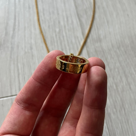 MM6 Maison Margiela gold-tone necklace featuring a polished ring pendant engraved with the brand’s signature number logo. Made in Italy from brass, the design includes a cable-link chain with adjustable length and lobster clasp fastening. A refined accessory that blends subtle branding with timeless elegance.