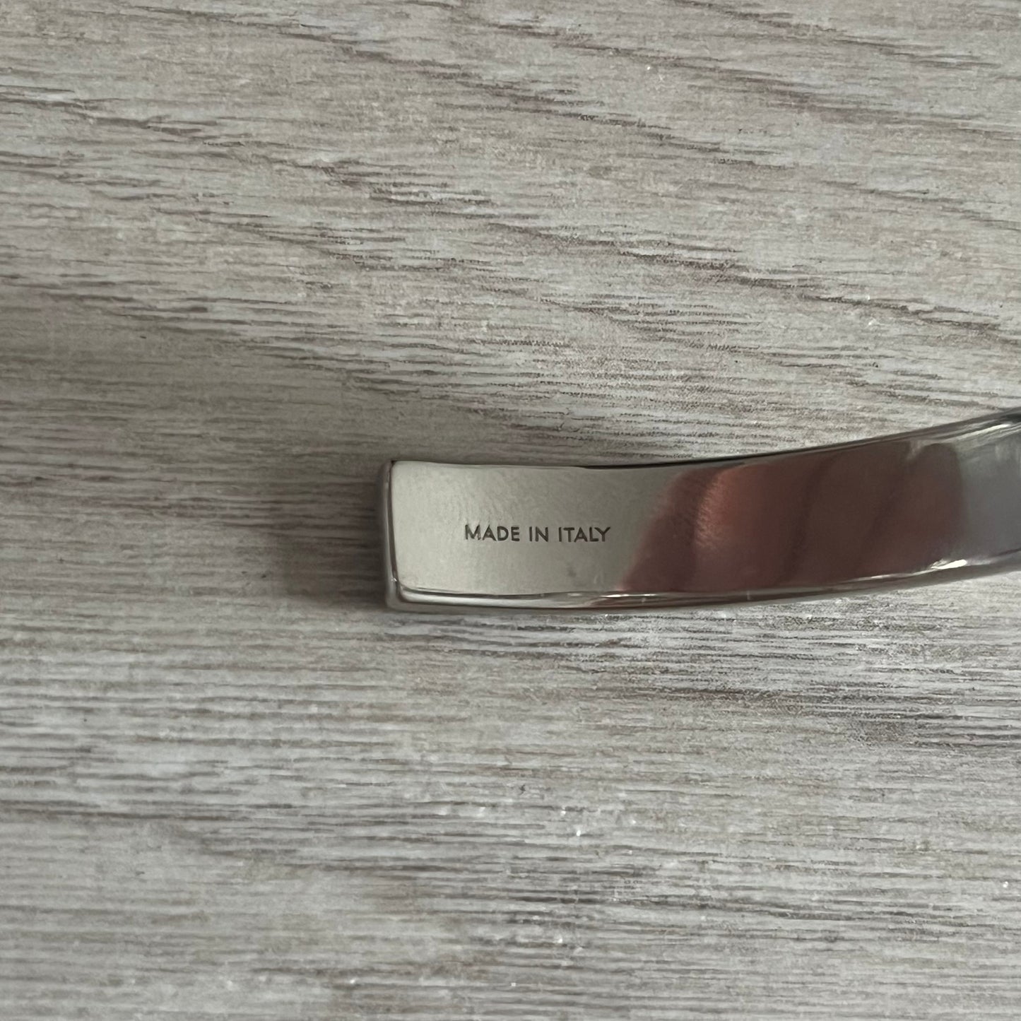Metallic object with 'MADE IN ITALY' engraving on a wooden surface