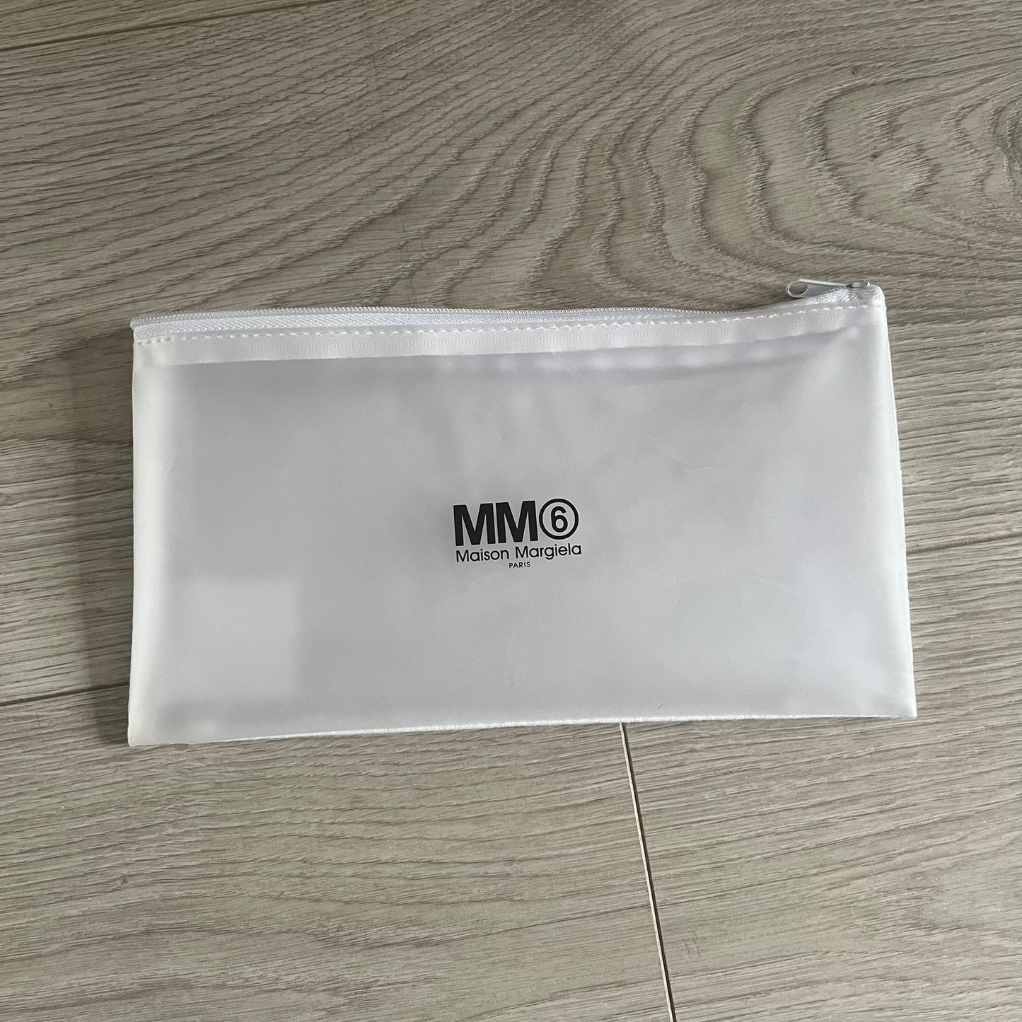 Clear pouch with MM6 Maison Margiela logo on a wooden surface