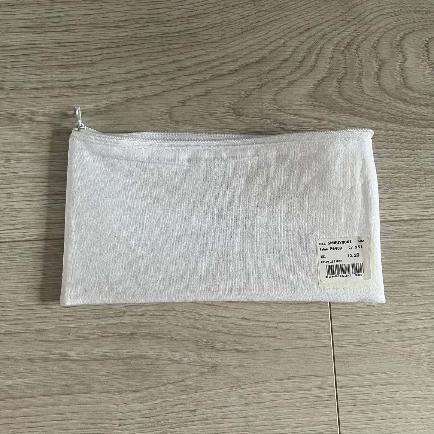 White zippered pouch with a label on a wooden surface