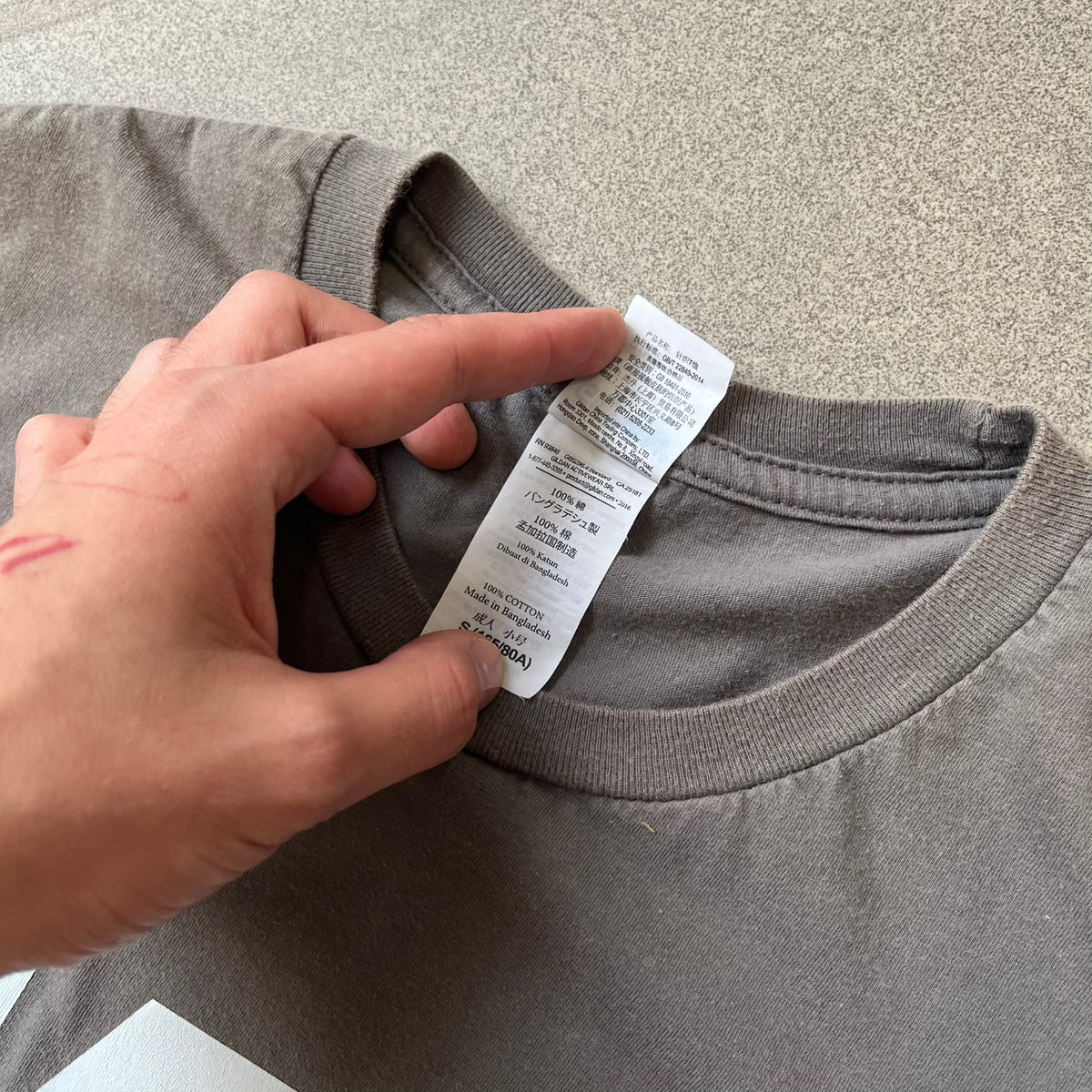 M&P by Smith & Wesson Gray Tee features a washed grey finish with a large M&P logo printed across the front and smaller "by Smith & Wesson" text underneath. Made from 100% cotton on a Gildan blank