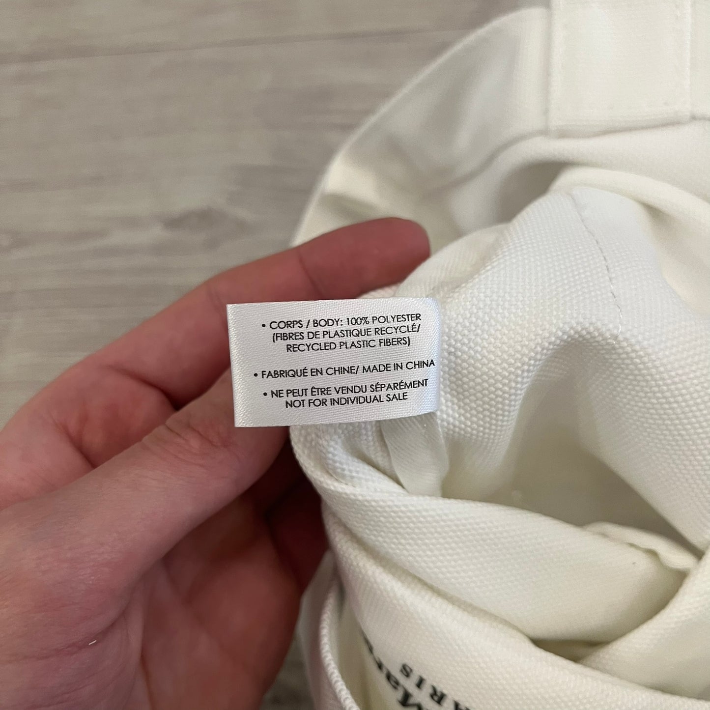 Maison Margiela Replica Tote Bag in off-white with a textured finish inspired by natural jute. Features “Replica” fragrances patch on one side, an interior slip pocket, and small “Maison Margiela Paris” text on the other side. Made in Paris, versatile for daily errands, work, or casual outings.