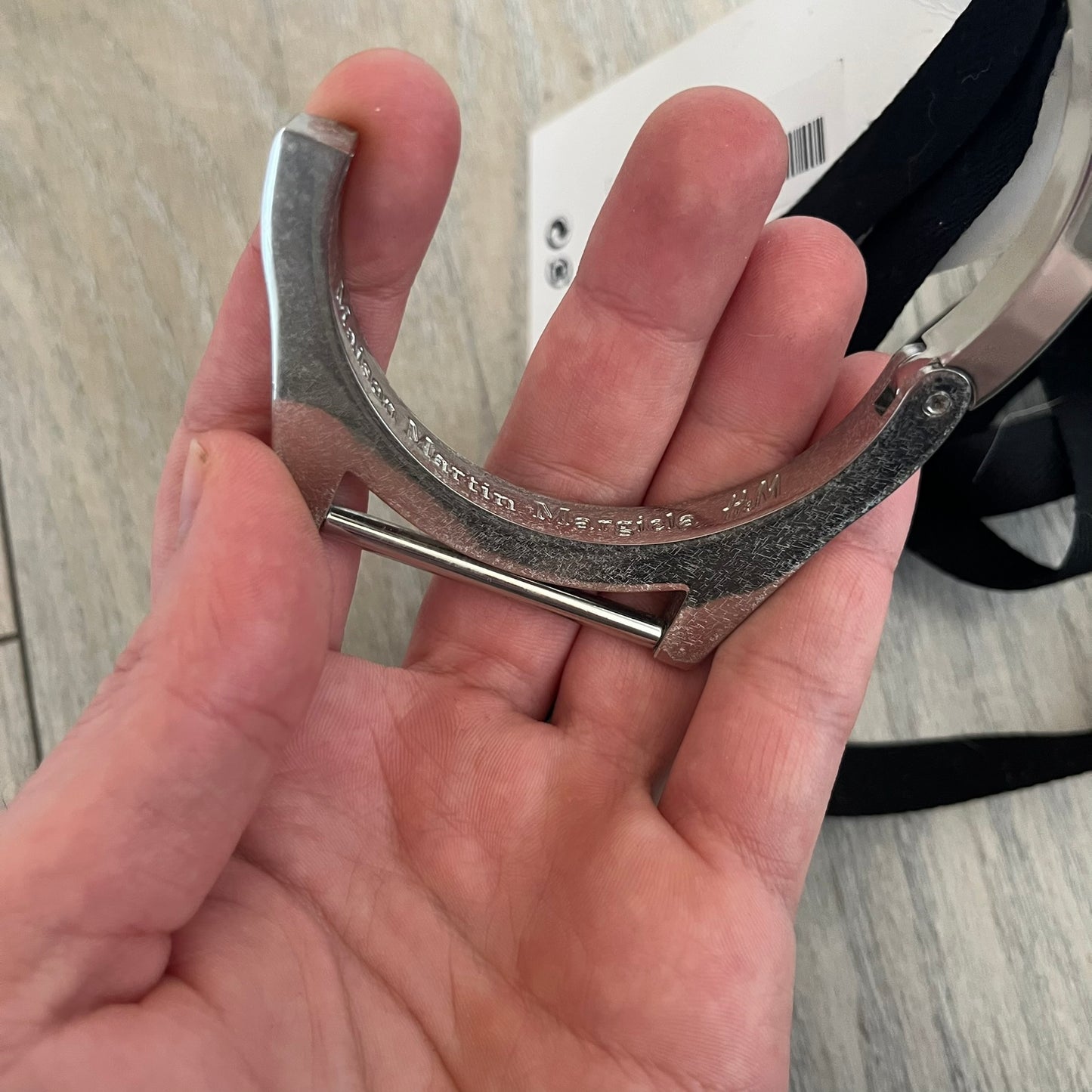 Maison Margiela x H&M AW09 Enlarged Watch Frame Bracelet is a stainless steel bracelet from the 2012 collaboration between Maison Margiela and H&M, based on an original Autumn/Winter 2009 design. The piece is shaped like an oversized watch case but functions as a bracelet, featuring a side clasp opening mechanism. It includes engraved tonal branding on the interior and can also be worn as a pendant. Made in Italy, it comes with the original tag.