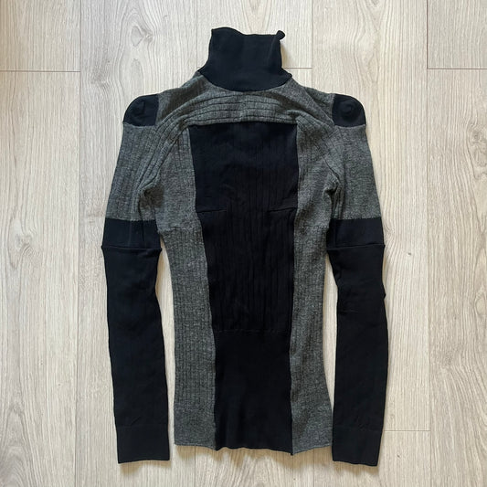 Maison Margiela x H&M AW12 wool sweater in gray and black, designed with stretch fabric for a snug, comfortable fit. Features sock-inspired panels with heel details on the shoulders and elbows, a turtleneck, and long sleeves. A standout piece from the 2012 collaboration, inspired by Margiela’s Fall 1989 collection.