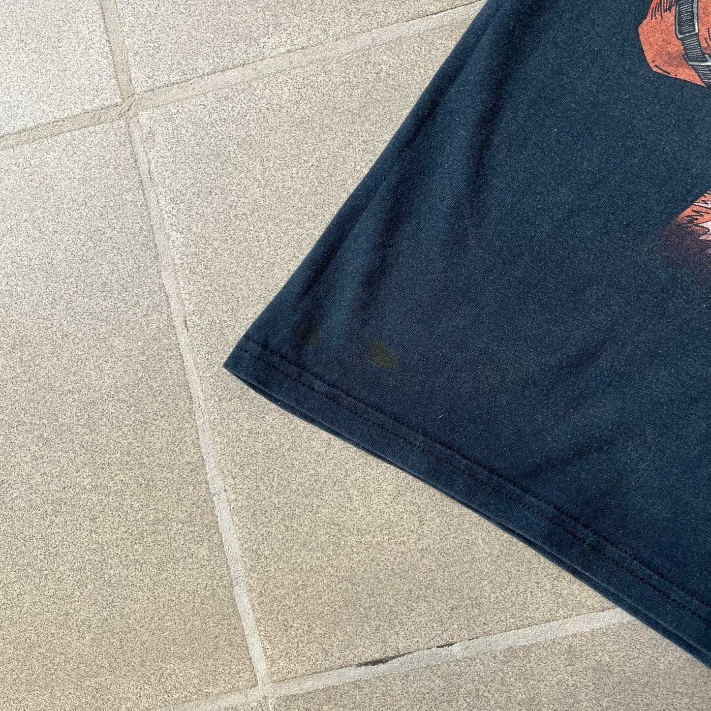 Marvel Mad Engine 2000's Deadpool Tee features a black T-shirt made by Mad Engine. The front has a comic-style graphic of Deadpool in mid-air firing two pistols, with bullets and bullet holes shown throughout the design.