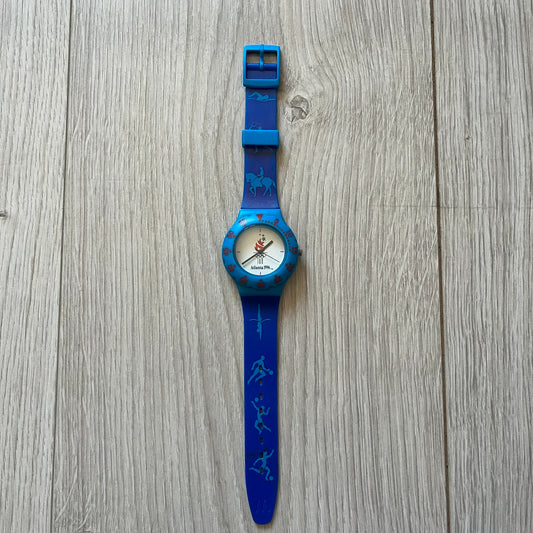 McDonald’s Atlanta 1996 Olympics analog watch with a dark blue strap featuring light blue sport-themed motifs. The dial is white with blue and red accents, showcasing the official Atlanta 1996 logo. A nostalgic collectible celebrating the iconic Olympic collaboration.