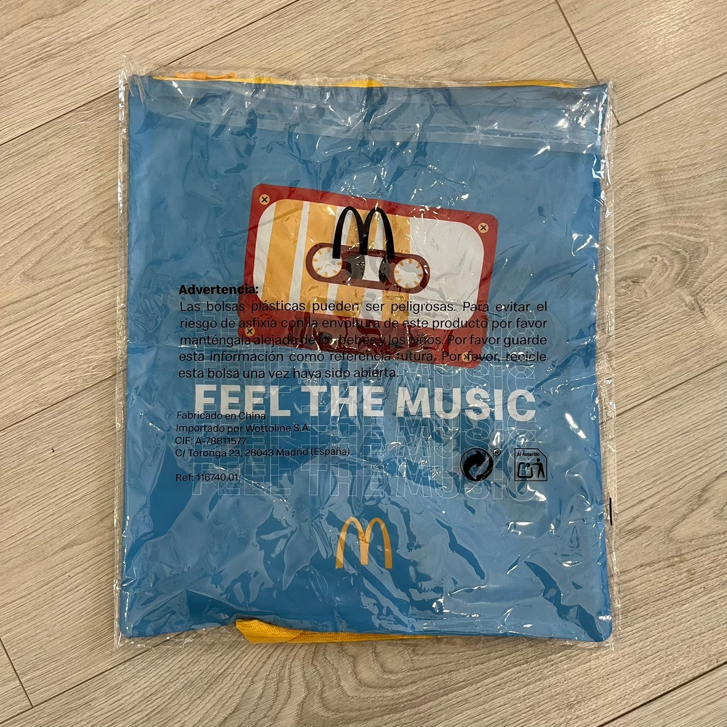 The McDonald’s Spain “Feel The Music” Backpack comes in a blue and yellow colorway with a vintage cassette graphic on the front. Constructed from lightweight non-woven synthetic fabric, it includes yellow straps and a zip-top closure. A collectible promotional item released by McDonald’s Spain.