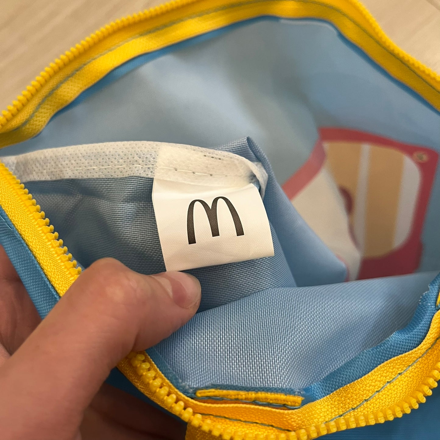 The McDonald’s Spain “Feel The Music” Backpack comes in a blue and yellow colorway with a vintage cassette graphic on the front. Constructed from lightweight non-woven synthetic fabric, it includes yellow straps and a zip-top closure. A collectible promotional item released by McDonald’s Spain.