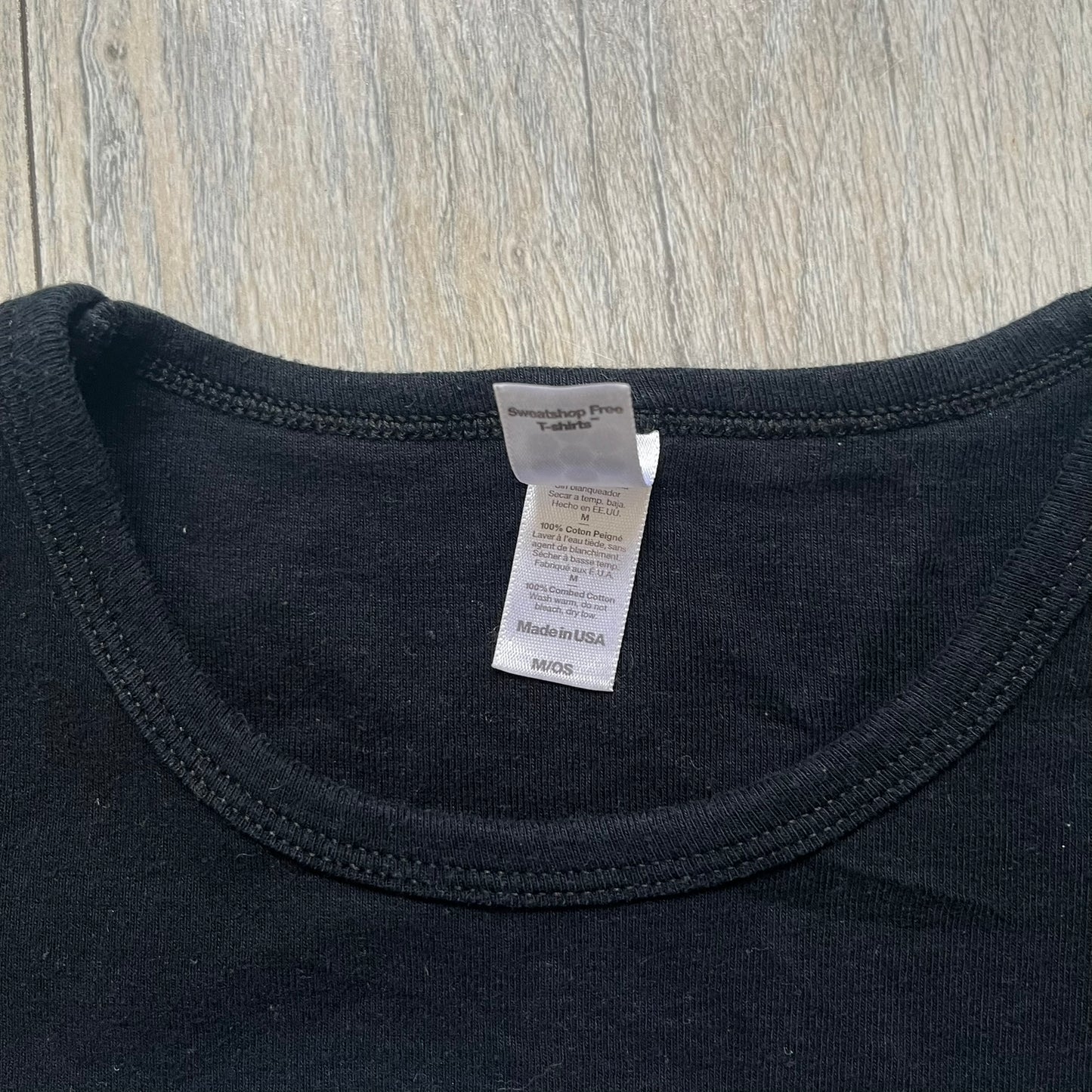 Misfits 2004 Fiend Skull Black Tee is a black T-shirt made in the USA on an American Apparel Classic Girl blank. The front features the band’s white Fiend Skull graphic printed on the chest. The shirt includes 2004 Cyclopian Music Inc. licensing and a Misfits neck tag.