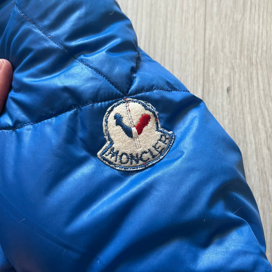 Vintage 1980s Moncler Grenoble down jacket in blue with a contrasting red lining. Features a foldable thin hood hidden in the back, silver-tone buttons and zippers, and the original Moncler patch on the sleeve. A rare French-made piece with authentic Grenoble labels, distinct from the brand’s modern ski line.