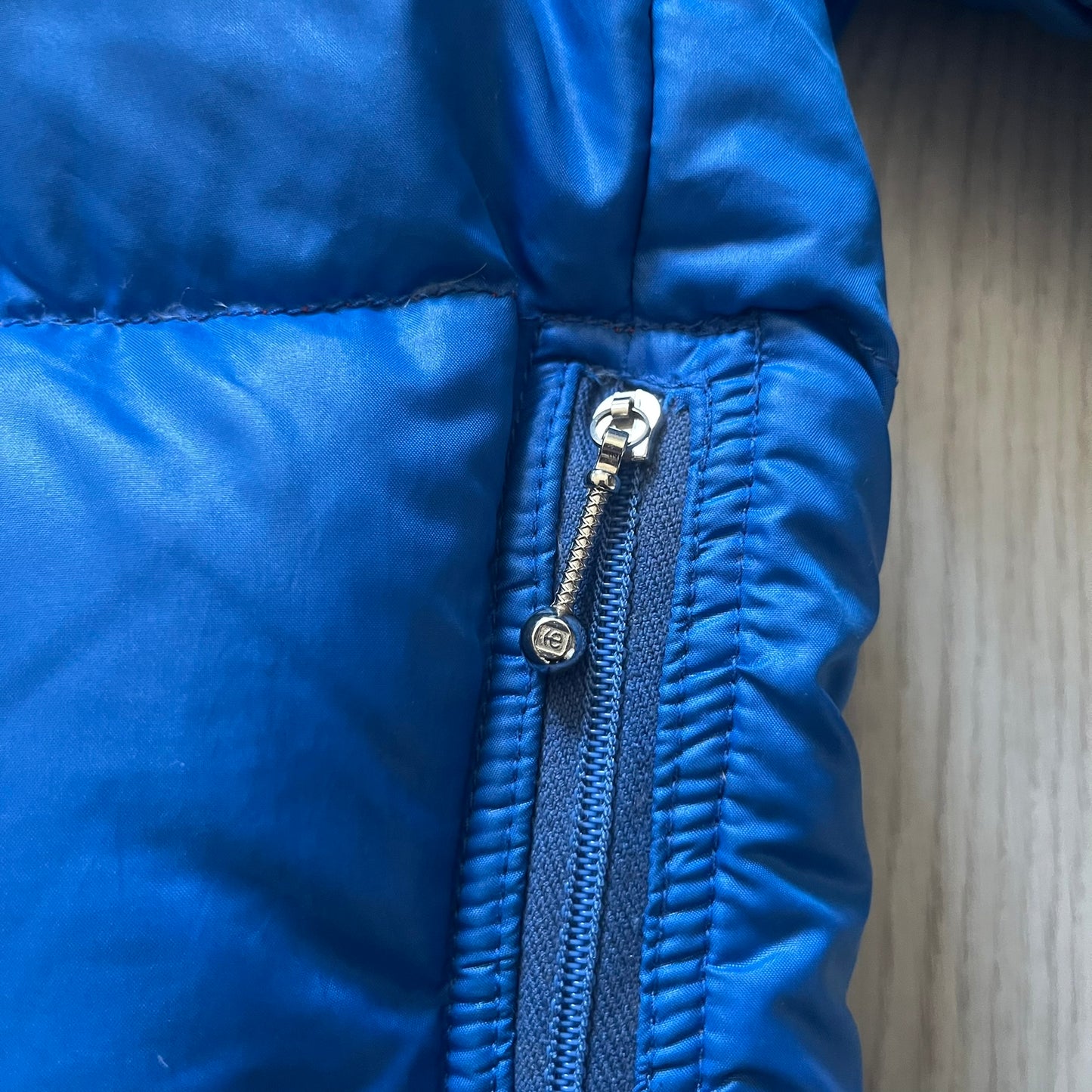 Vintage 1980s Moncler Grenoble down jacket in blue with a contrasting red lining. Features a foldable thin hood hidden in the back, silver-tone buttons and zippers, and the original Moncler patch on the sleeve. A rare French-made piece with authentic Grenoble labels, distinct from the brand’s modern ski line.
