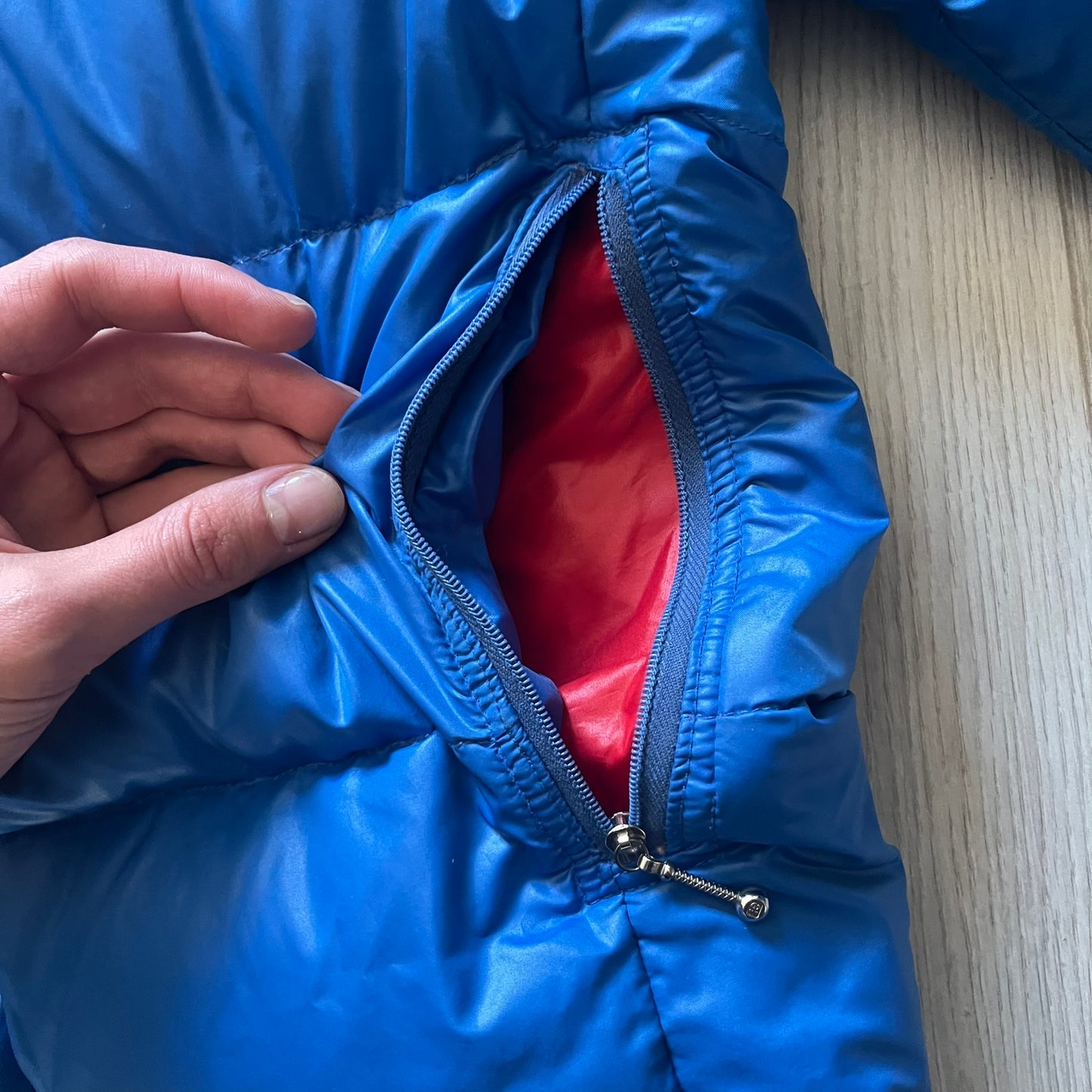 Vintage 1980s Moncler Grenoble down jacket in blue with a contrasting red lining. Features a foldable thin hood hidden in the back, silver-tone buttons and zippers, and the original Moncler patch on the sleeve. A rare French-made piece with authentic Grenoble labels, distinct from the brand’s modern ski line.