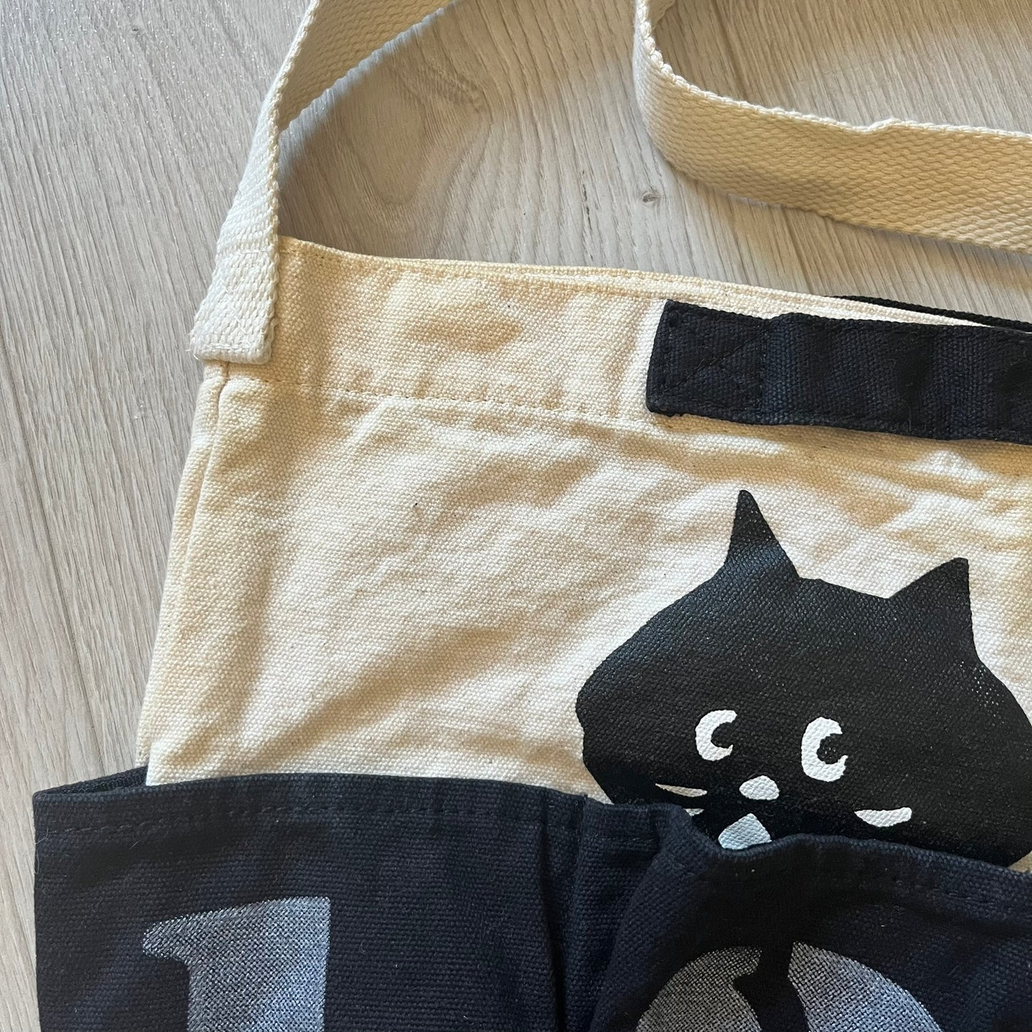Beige apron with black cat design on a wooden surface