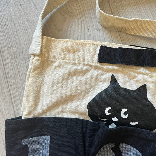 Beige apron with black cat design on a wooden surface