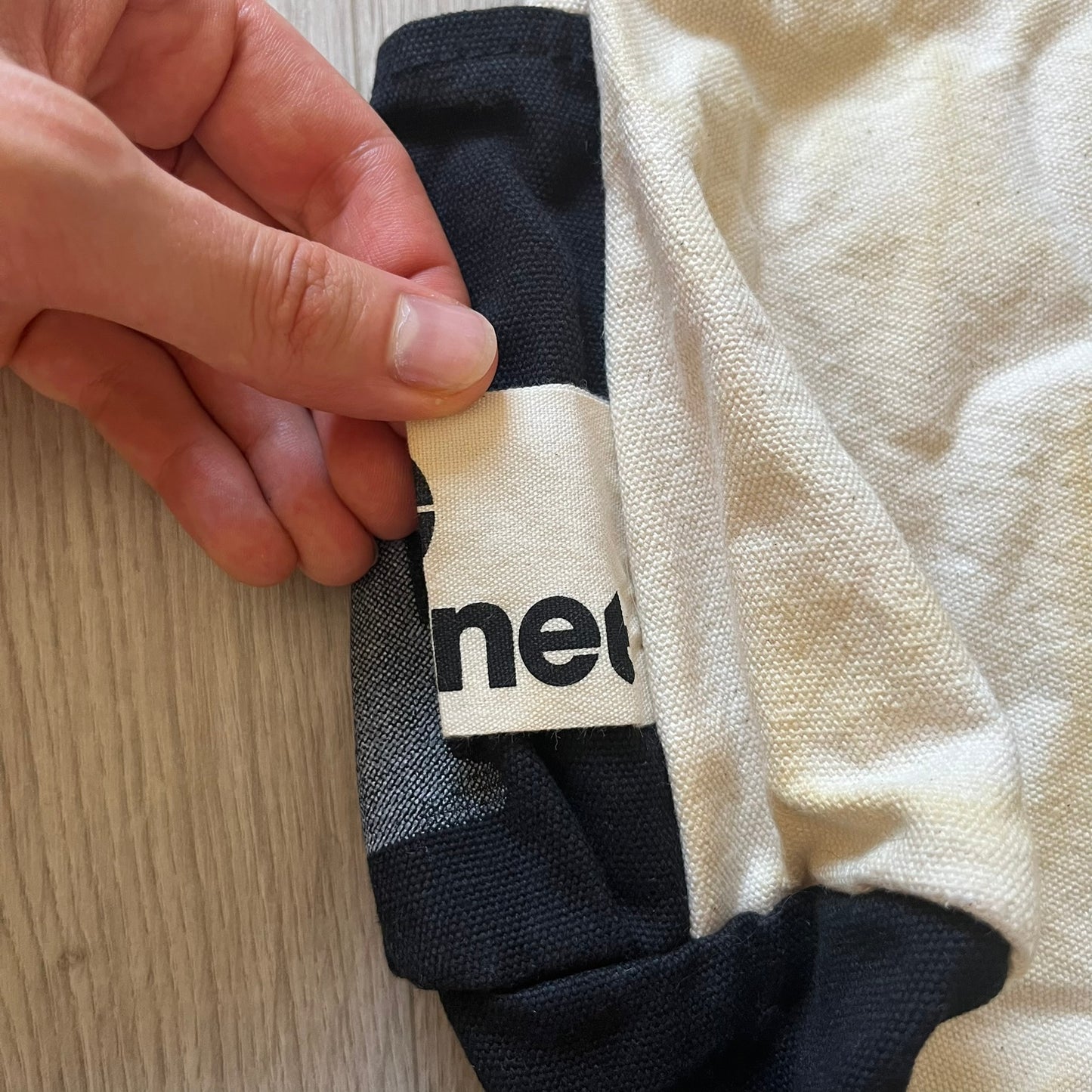 Close-up of a hand holding a black and white sock with 'neo' branding.