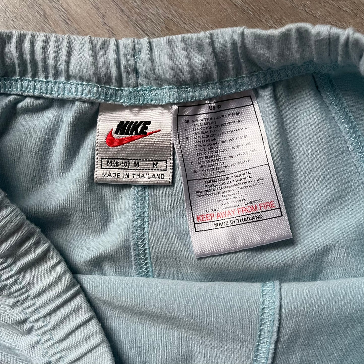 Nike 90’s Challenge Court Tennis Skirt is a baby blue women’s tennis skirt made in Thailand. It features a small green and red Nike Court logo patch at the lower hem, a Dri-FIT patch at the top, and an adjustable waistband with drawstrings. 