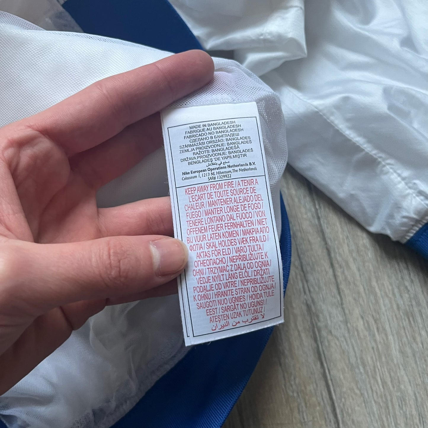 Nike Brazil windbreaker released in 2008 to mark the 50th anniversary of Brazil’s football legacy. Features a split color-block design with white lower panels and sleeves, yellow and green upper section, blue cuffs and hems, and a green hood. Detailed with a gold embroidered Nike logo on the chest, a gold-tone metal Brazil crest pin on the opposite side, and “1958-2008” with a “50” printed on the hood. The hood interior is white with an all-over green star pattern.