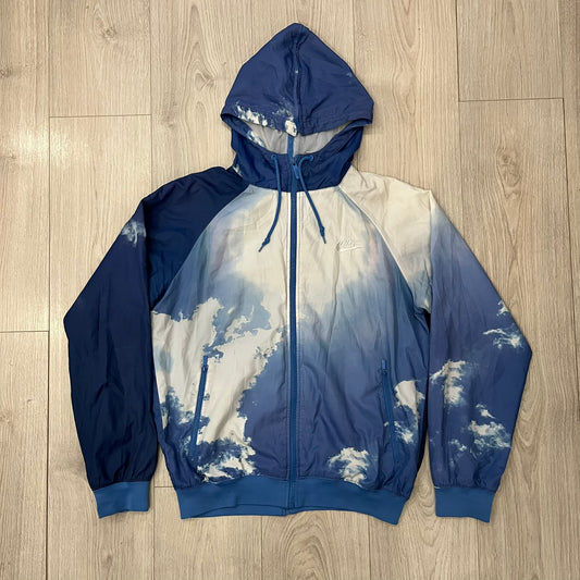 Nike Cloud Day Split Windbreaker from the 2010s in full blue with a photorealistic all-over cloud print. Features dual zippers on the front and back, allowing the jacket to split in half and merge with other compatible pieces. Made from 100% nylon.