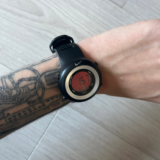 Nike Georg WK0010 digital watch with a bold red dial and black case accented by a silver aluminum bezel. Features include chronograph, alarm, time, and date functions with a 12-hour display and backlight. Water-resistant up to 50m with a durable black silicone strap.