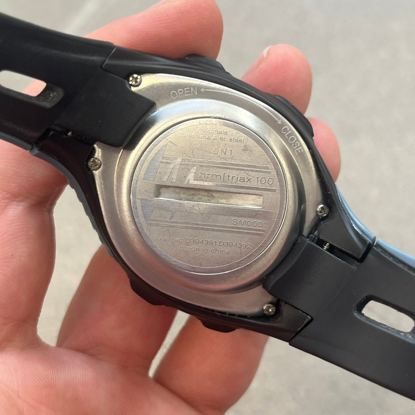 Nike HRM Triax 100 SM0001 Digital Watch features a black rubber strap with a silver-tone case and black Nike Swoosh branding. The watch includes four side buttons and a dedicated white front button for the backlight function. It has a digital display with 100-lap memory, multiple training modes, and performance tracking functions, designed for sports and active use.