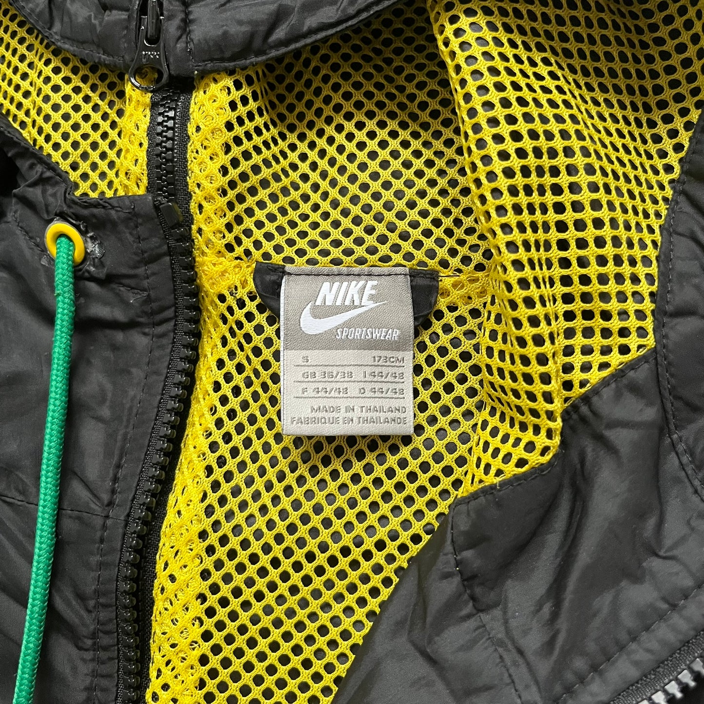 Nike Jamaica Olympics 2008 Split Windbreaker designed by Jarrett Reynolds. Features a black base with a yellow cross on the front inspired by the Jamaican flag. Green bottom hem and details. Dual side zippers allow the jacket to split in half and be combined with other pieces from the collection, with a small Jamaica flags detail inside the pocket.