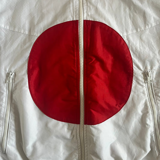 Nike Japan Olympics Split Windbreaker from 2008, created by designer Jarrett Reynolds. Crafted in white with a large red circle representing Japan’s flag, this innovative jacket can be zipped apart on both sides and merged with other compatible models. Hidden inside, a small Japan flags accent completes the concept.